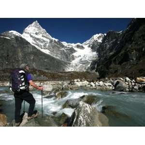 Trekker Pauses for a Break on the Edge of a Glacial Stream on the Way 